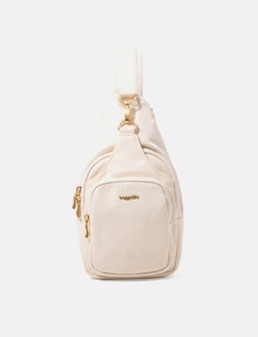 Cream sling bag with gold-tone hardware, multiple zippered compartments, and a compact hands-free design.