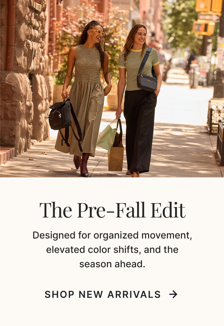 Two women walking through a city street carrying Baggallini handbags from the Pre-Fall collection, showcasing elevated everyday style.