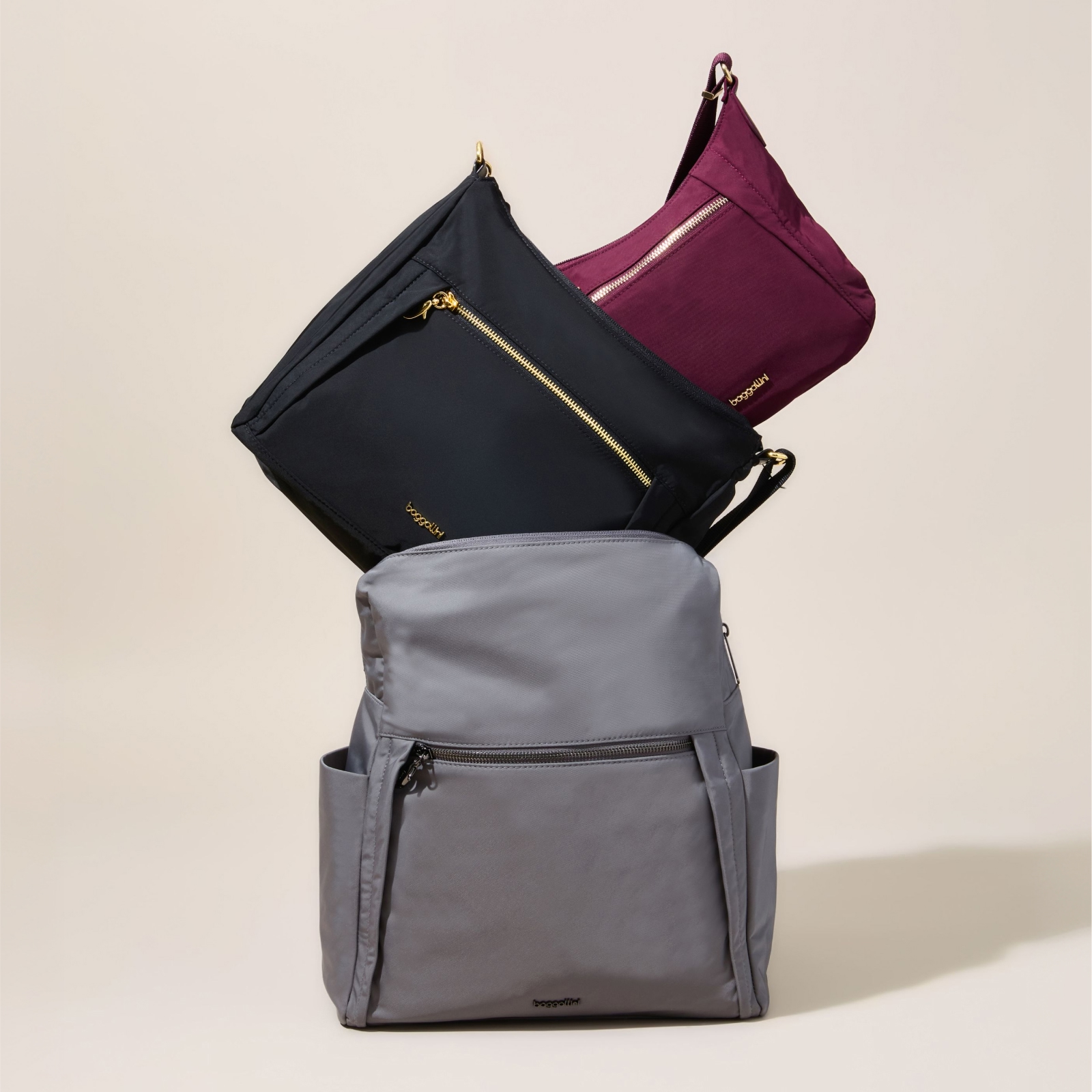 Gray Baggallini backpack styled with black, burgundy and gray shoulder bags.
